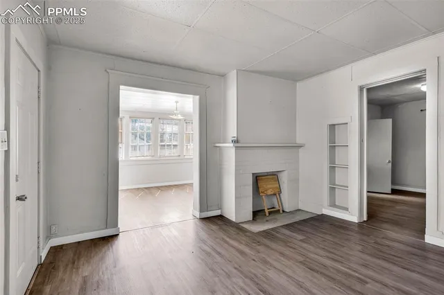 an empty room with wooden floor fireplace and windows