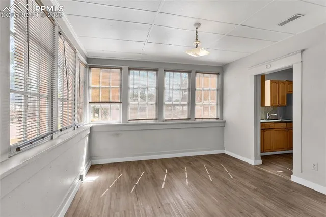 a view of an empty room with a window and wooden floor