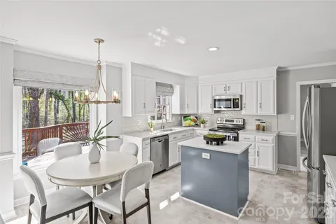 a kitchen with stainless steel appliances a dining table a stove a refrigerator a dining table and chairs