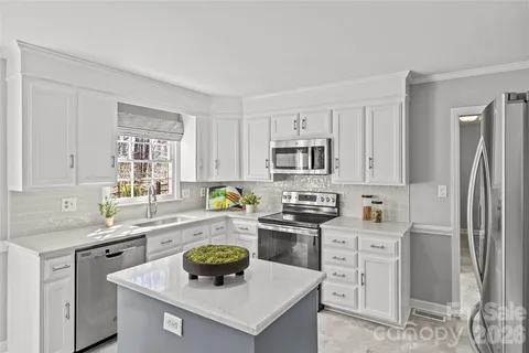 a kitchen with stainless steel appliances a sink a stove a refrigerator cabinets and a window