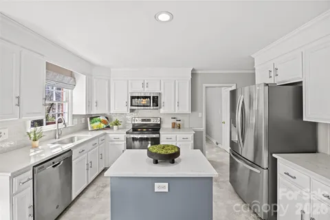a kitchen with stainless steel appliances a sink dishwasher a refrigerator a stove top oven a counter space and cabinets