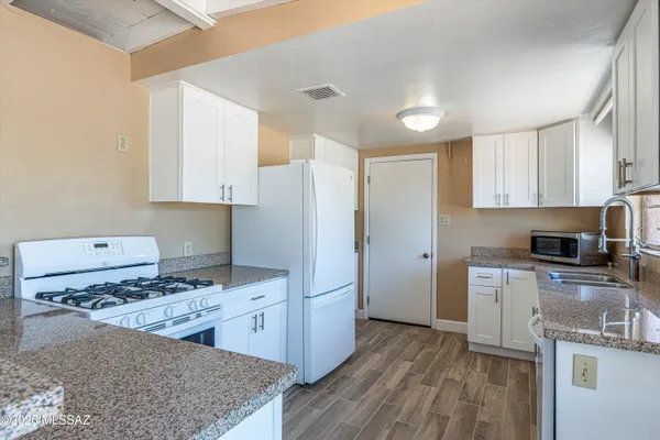a kitchen with stainless steel appliances granite countertop a refrigerator stove sink and wooden cabinets
