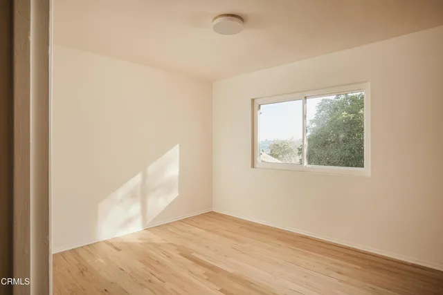 a view of an empty room with wooden floor and a window