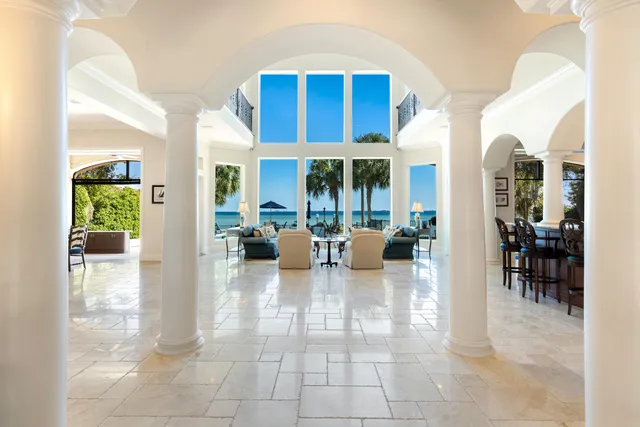 a view of a swimming pool with a patio and a yard with palm trees