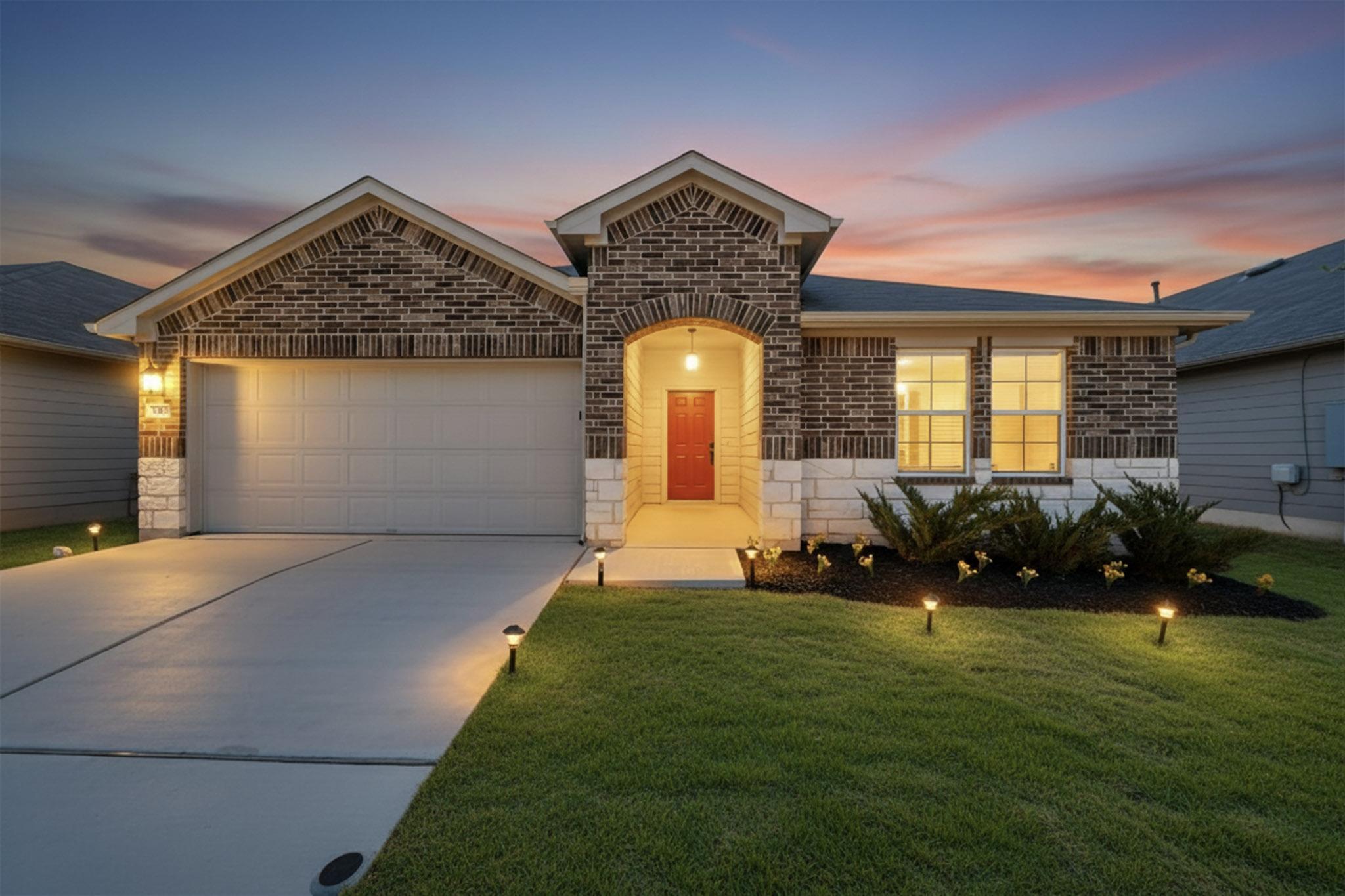 218 Sickle Loop Kyle, TX 78640 - Photo 1 of 1 View of front facade with stone siding, brick siding, driveway, a garage, and a lawn