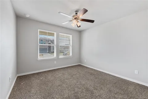 an empty room with window and ceiling fan