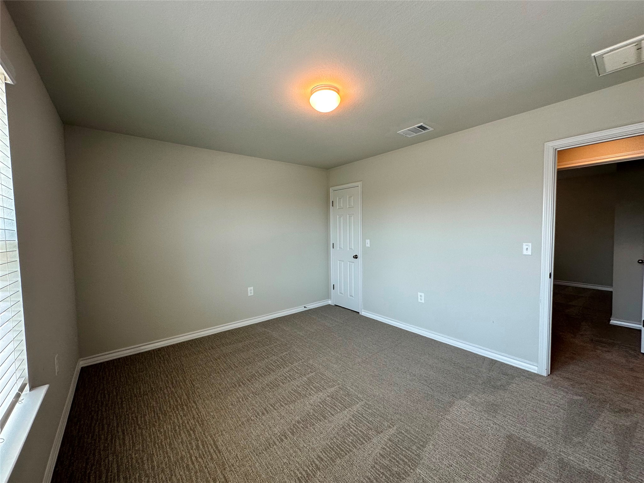 1624 Caballo Blanco Road Austin, TX 78725 - Photo 16 of 23 A well-lit room with ample space, featuring fresh carpeting and a standard door.