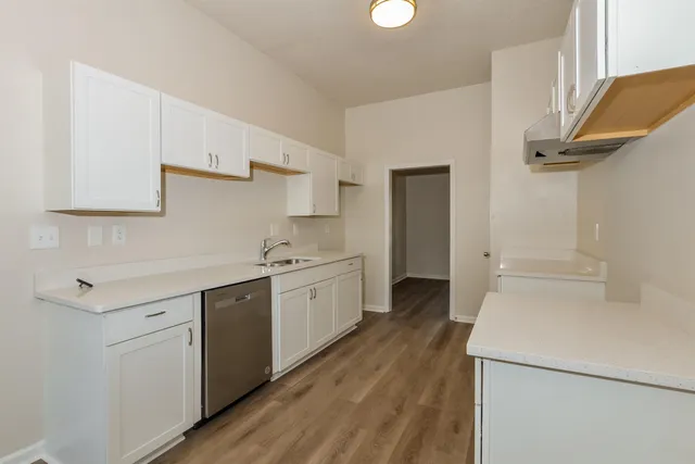 a kitchen with a sink a stove cabinets and wooden floor