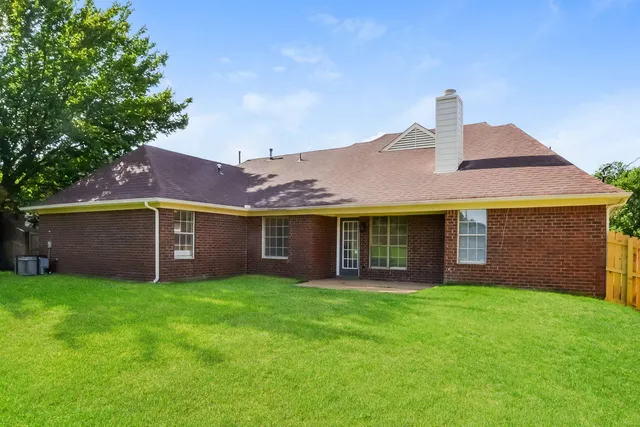 a view of a house with a yard and a large tree
