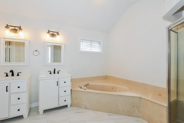 a bathroom with a tub sink and mirror