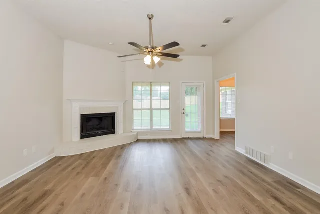 a view of a livingroom with a fireplace a ceiling fan and hardwood floor