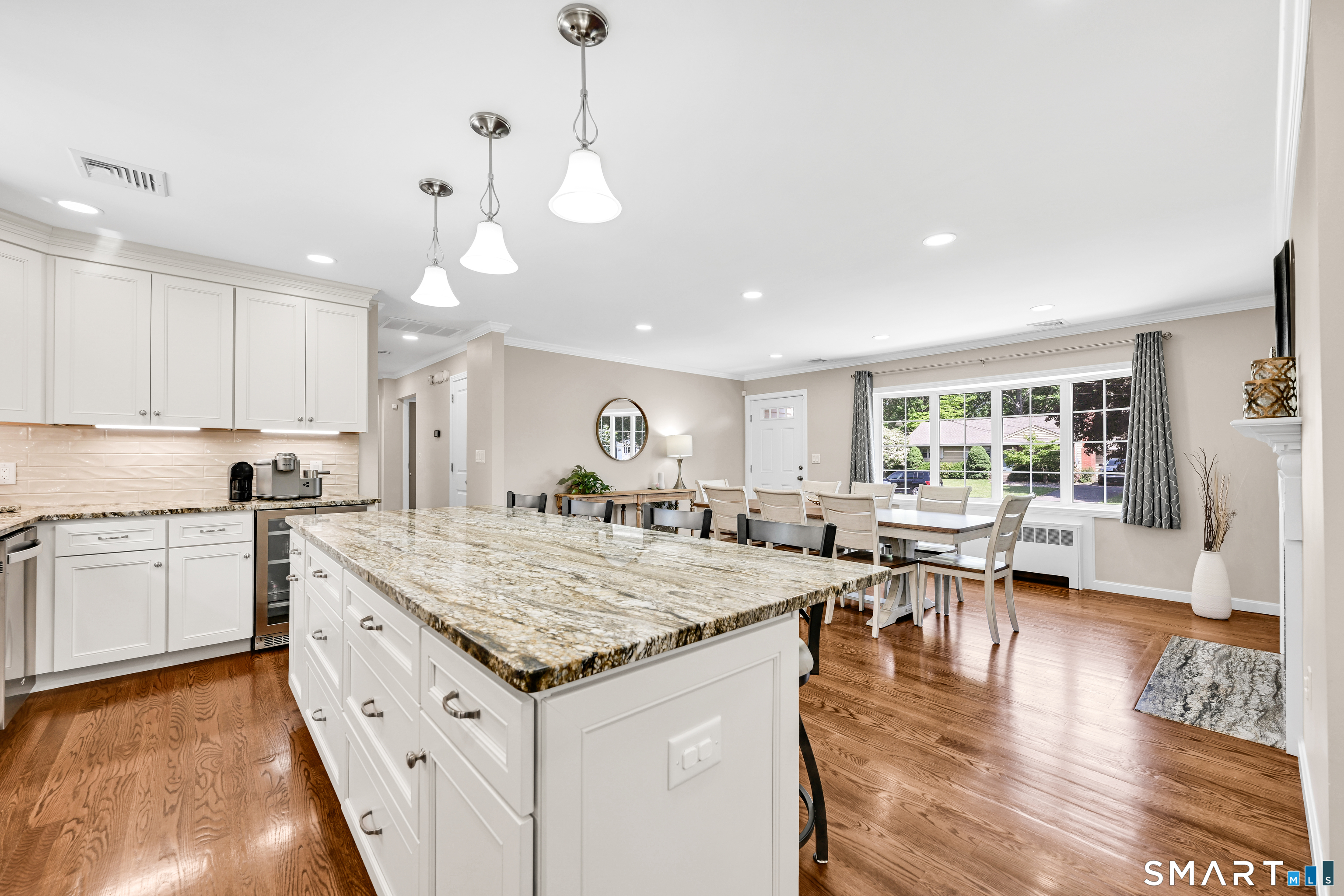 87 Lydall Road Newington, CT 06111 - Photo 12 of 35 a open kitchen with kitchen island a stove a sink a dining table and chairs with wooden floor