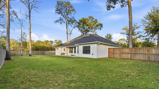 a white house with a small yard and wooden fence