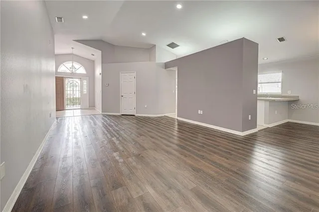 an empty room with wooden floor chandelier fan and window