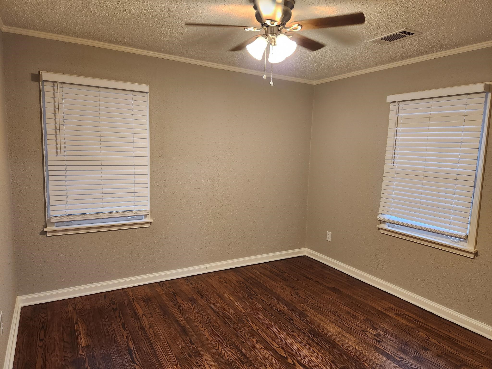 866 Colonial Road Memphis, TN 38117 - Photo 13 of 15 Empty room featuring a textured ceiling, dark wood-type flooring, ornamental molding, ceiling fan, and a textured wall