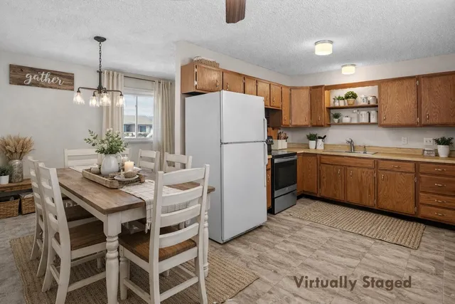 a kitchen with stainless steel appliances a refrigerator a sink a stove a dining table and chairs