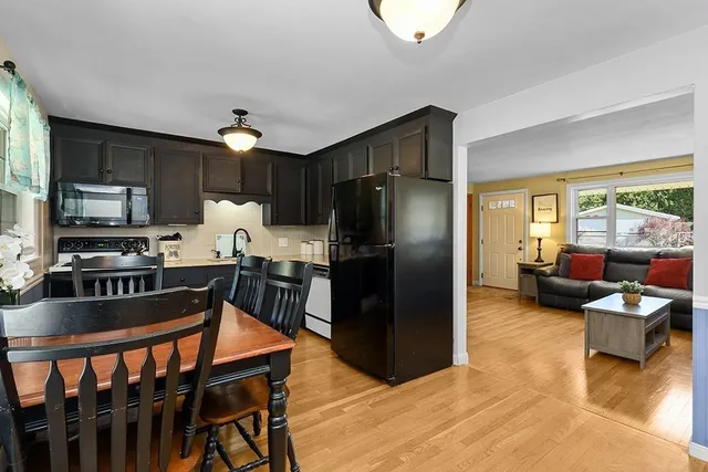 a kitchen with stainless steel appliances granite countertop a refrigerator a stove a sink a dining table and chairs