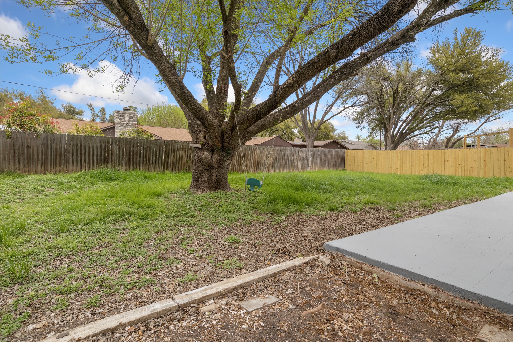 502 Pin Tail Lane Taylor, TX 76574 - Photo 22 of 26 Expansive backyard featuring a mature central tree, a concrete patio, and a combination of wood privacy fencing
