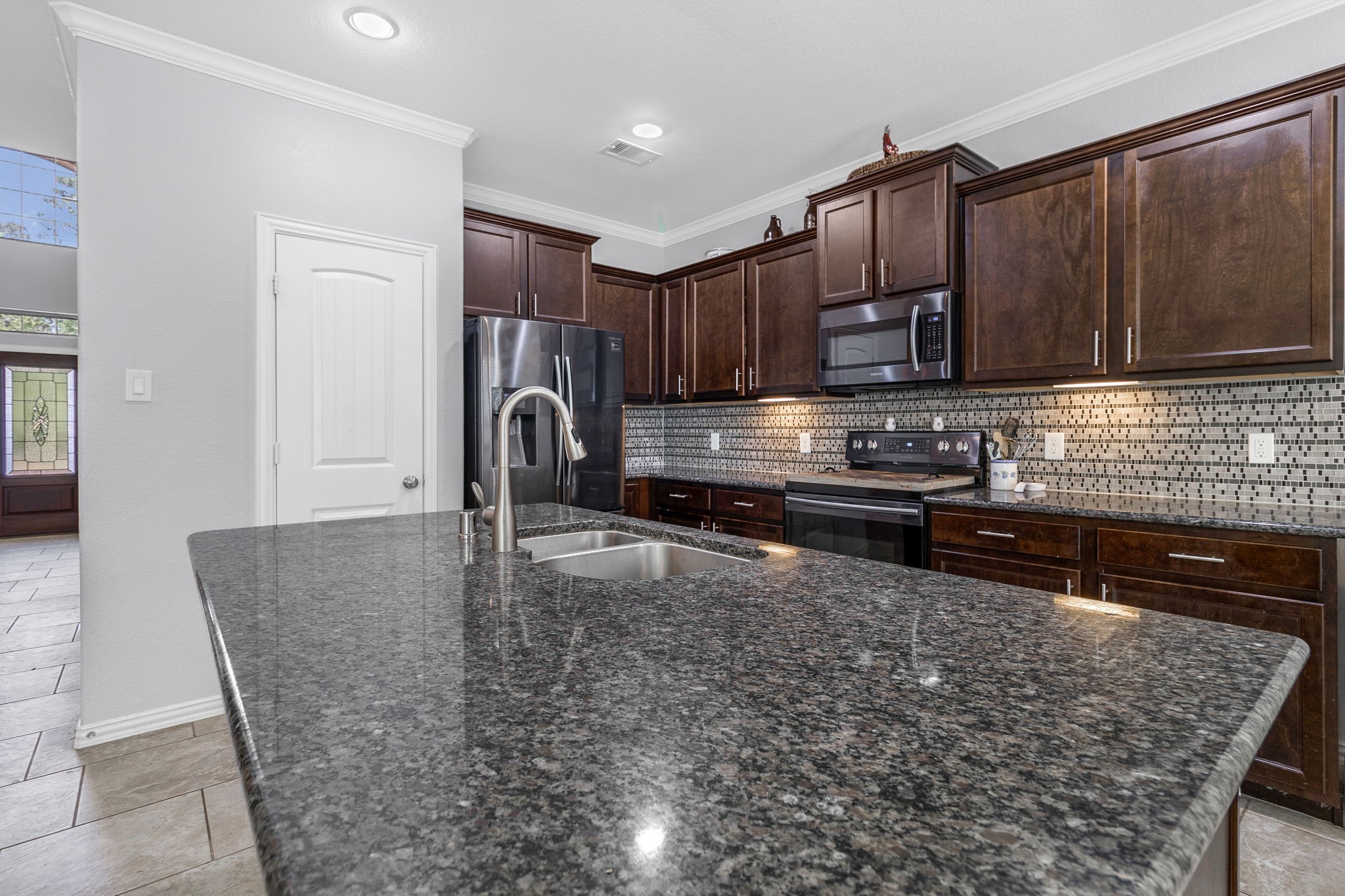 9014 San Saba Way Willis, TX 77378 - Photo 6 of 18 a kitchen with kitchen island granite countertop a stove and cabinets