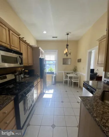 a kitchen with stainless steel appliances granite countertop a stove a refrigerator and a microwave