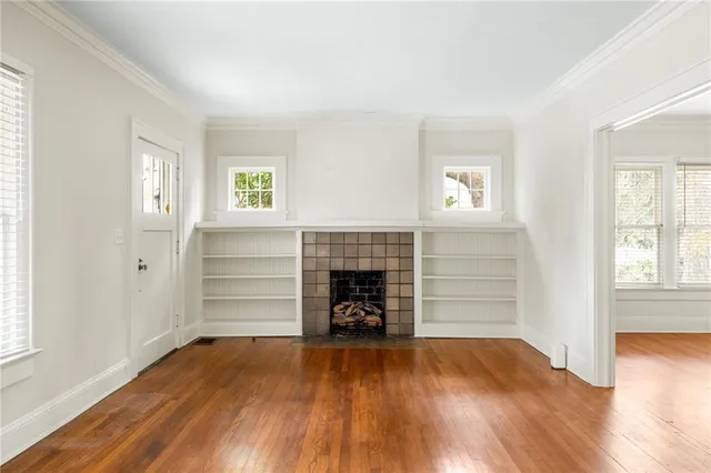 an empty room with wooden floor fireplace and windows