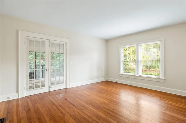 a view of an empty room with wooden floor and a window