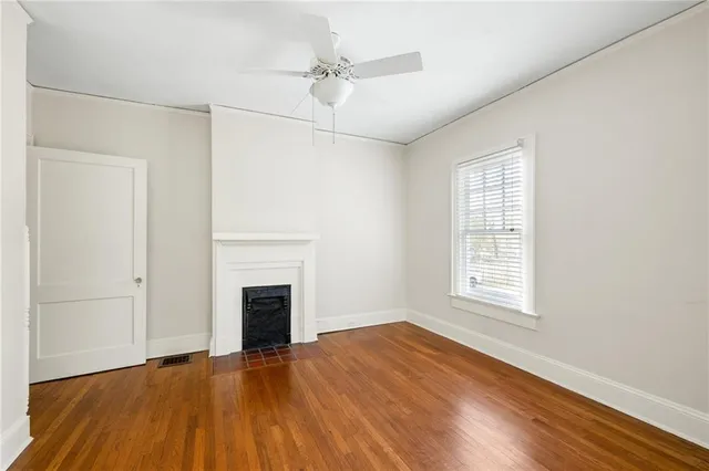 an empty room with wooden floor fireplace and windows
