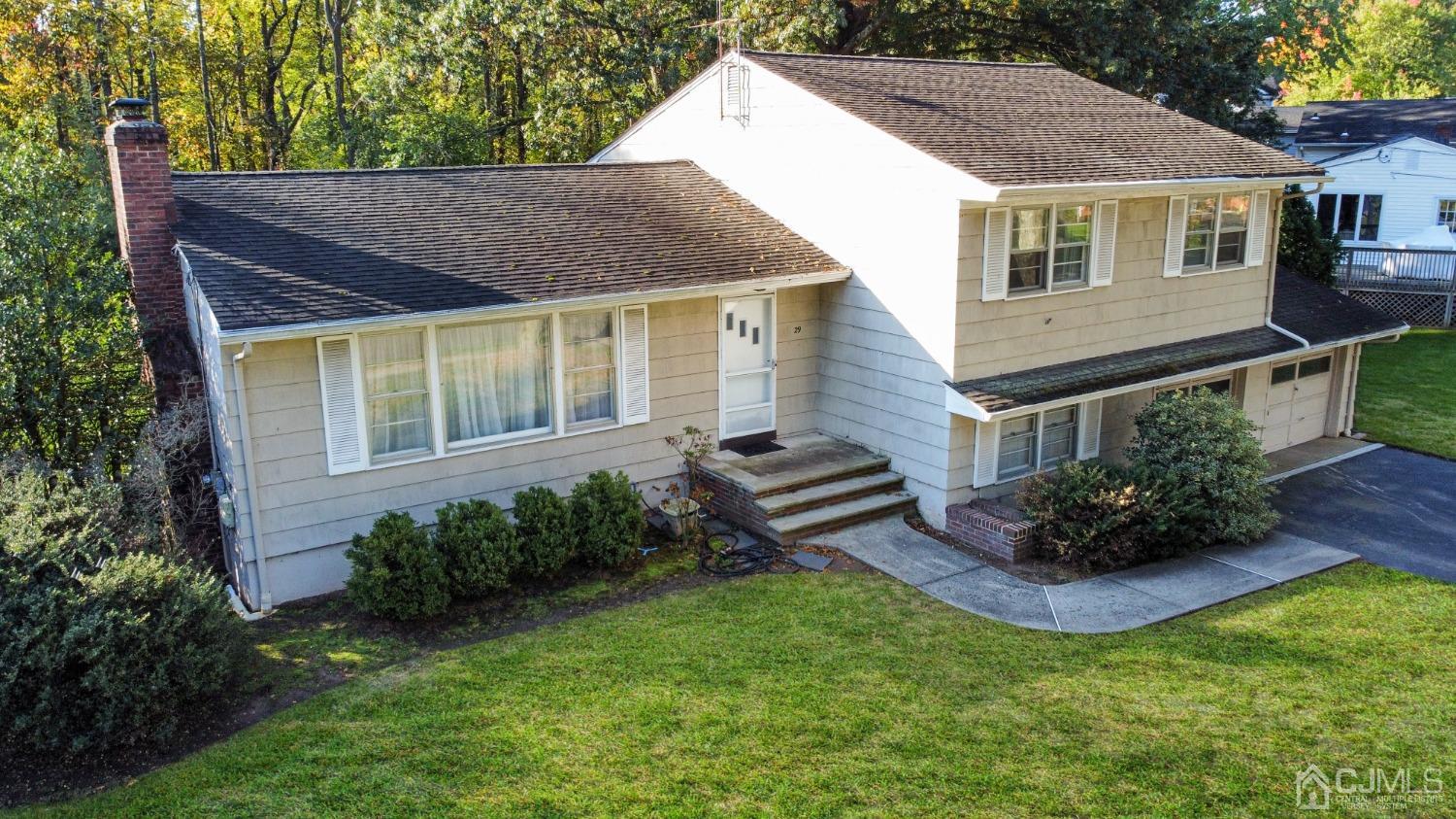 a view of a house with a yard plants and large tree
