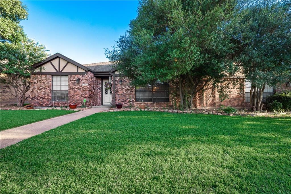 a view of a house next to a big yard and large trees