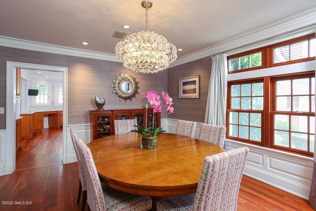 a dining room with wooden floor a chandelier a wooden table and chairs