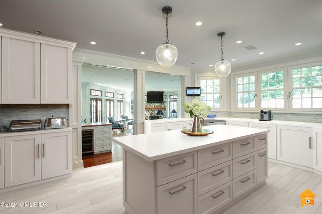 a large kitchen with granite countertop a large kitchen island white cabinets and stainless steel appliances