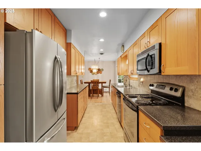 a kitchen with stainless steel appliances granite countertop a refrigerator a stove and a sink