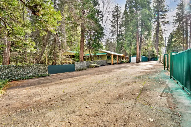a view of a house with large trees and playing ground