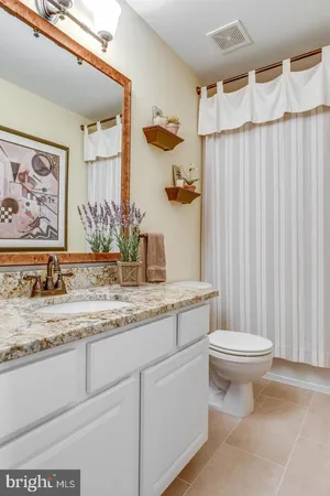 a bathroom with a granite countertop sink a toilet and a mirror
