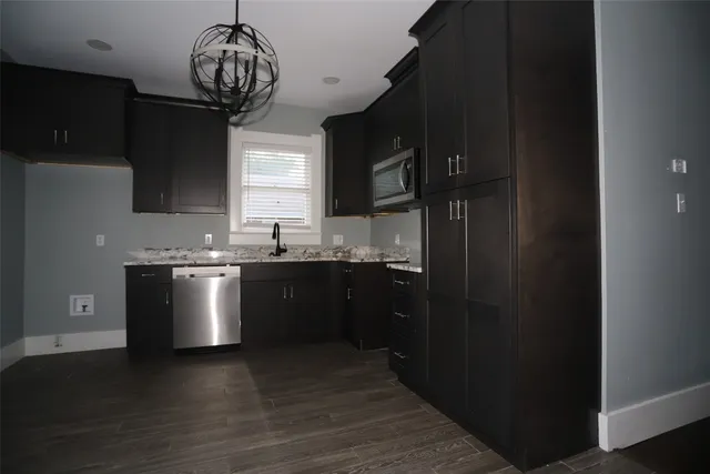 a kitchen with stainless steel appliances granite countertop a refrigerator a sink dishwasher a stove and white countertops with wooden floor