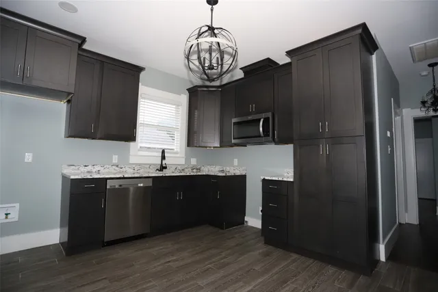 a kitchen with stainless steel appliances granite countertop a refrigerator a sink dishwasher a stove and a microwave oven on granite countertops