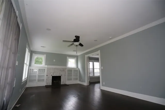 an empty room with wooden floor fireplace and windows