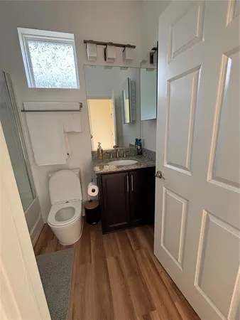 a bathroom with a toilet a sink a mirror a window and vanity