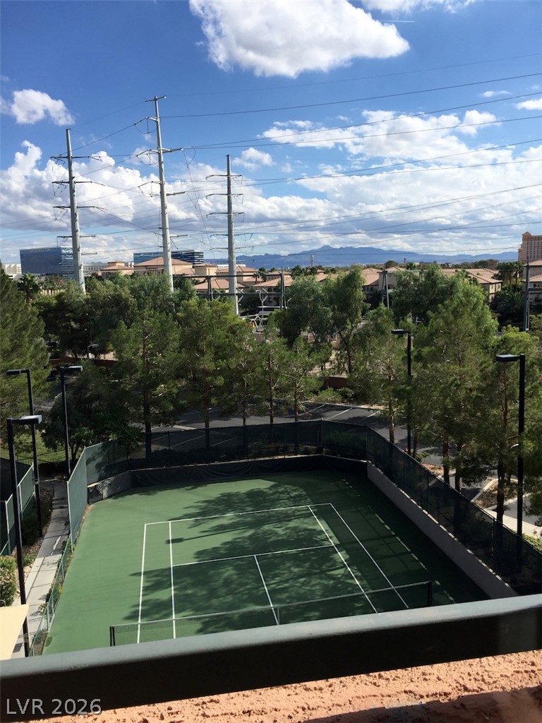 230 East Flamingo Road, Unit 404 Las Vegas, NV 89169 - Photo 30 of 34 An elevated perspective overlooks a green tennis court bordered by mature trees and mountain views.