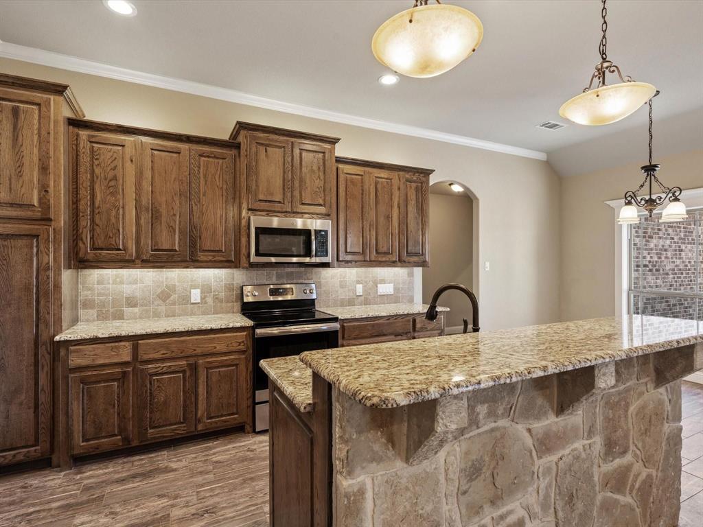 229 Etta Lane Springtown, TX 76082 - Photo 13 of 39 a kitchen with kitchen island granite countertop a stove a sink and a microwave