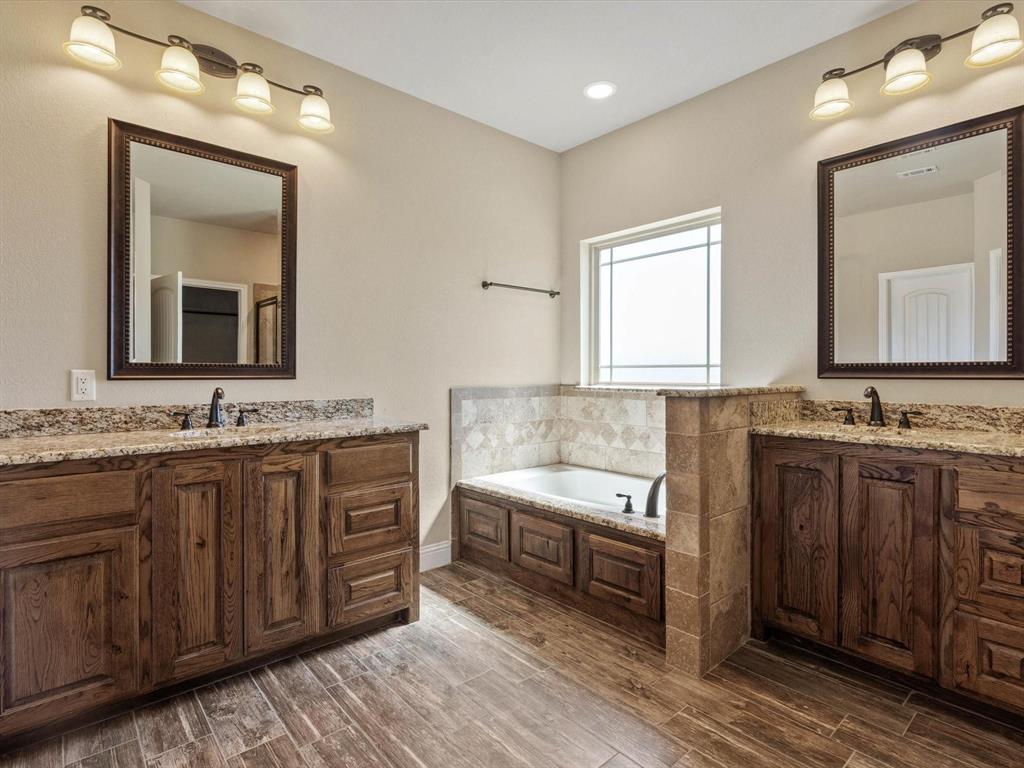 229 Etta Lane Springtown, TX 76082 - Photo 25 of 39 a bathroom with a granite countertop double vanity sink a mirror and a bathtub