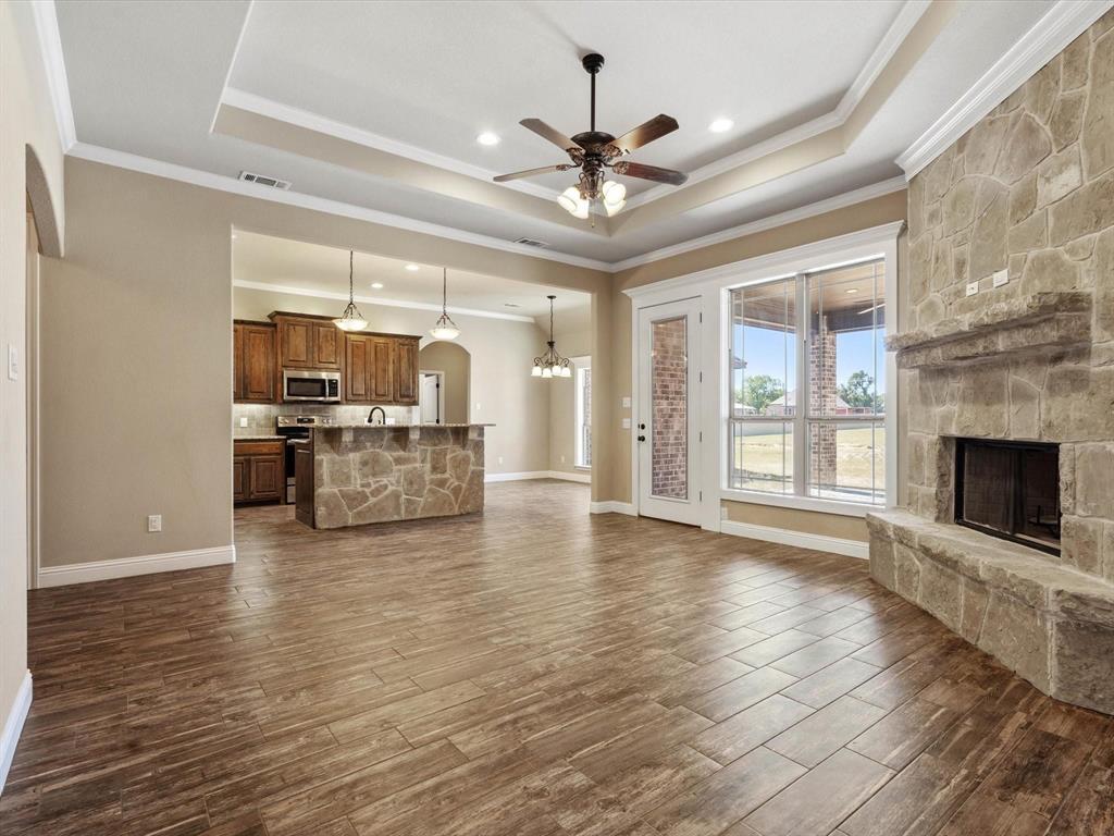 229 Etta Lane Springtown, TX 76082 - Photo 9 of 39 a view of a big room with wooden floor a kitchen view and a fireplace