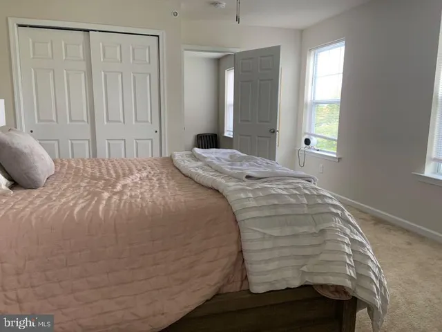a bed sitting in a spacious bedroom next to a window