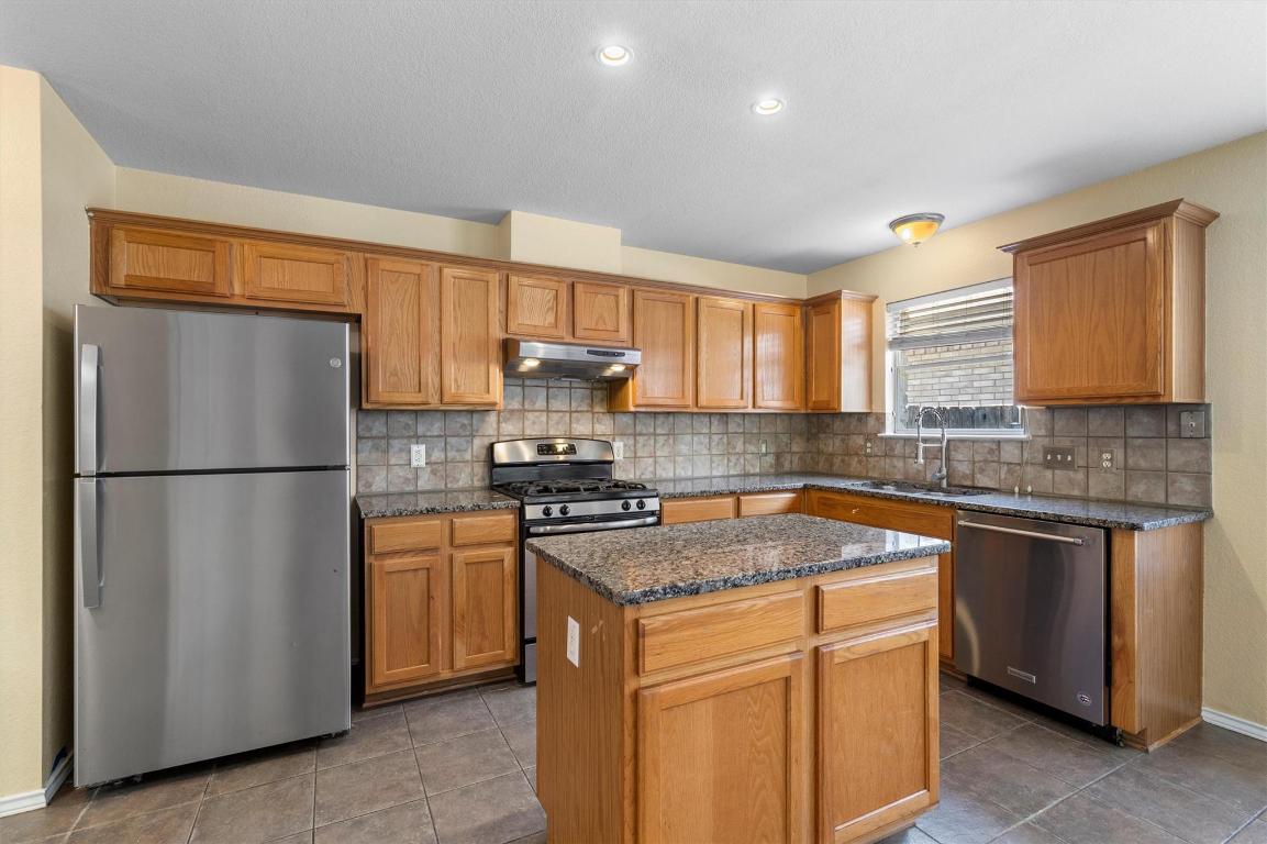 8336 Alvin High Lane Austin, TX 78729 - Photo 11 of 40 Kitchen with appliances with stainless steel finishes, backsplash, dark stone countertops, dark tile patterned floors, and recessed lighting
