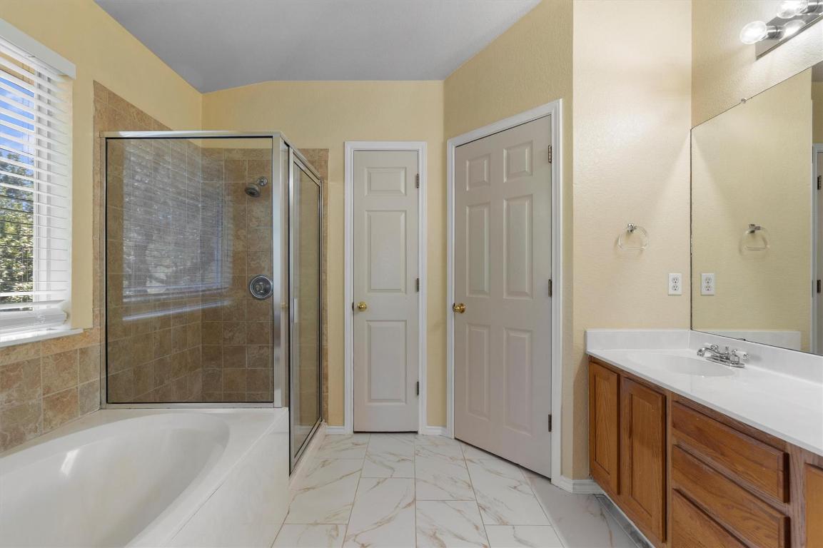 8336 Alvin High Lane Austin, TX 78729 - Photo 24 of 40 Bathroom with vanity, a stall shower, a bath, and light marble finish floors