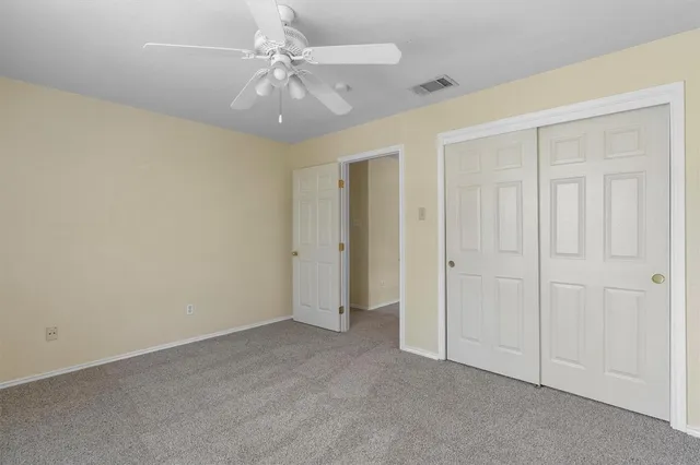 a view of an empty room with chandelier fan and fire place