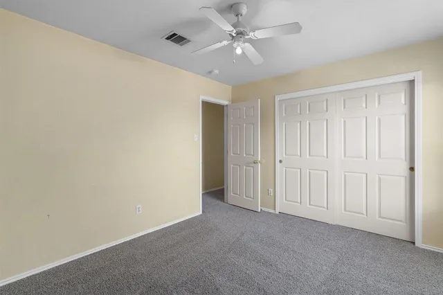 an empty room with a chandelier fan and windows