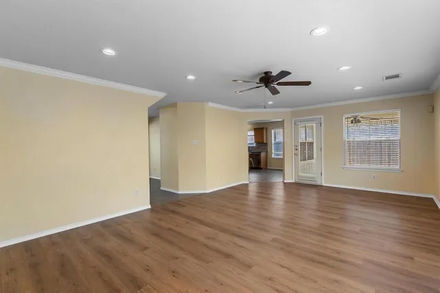 a view of an empty room with a window and wooden floor