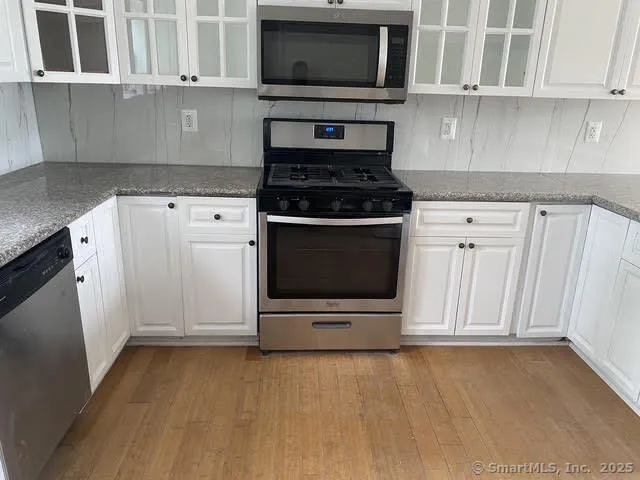 a kitchen with stainless steel appliances granite countertop a stove microwave and cabinets