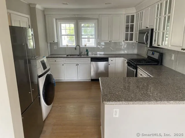 a kitchen with stainless steel appliances granite countertop a sink a stove a microwave a refrigerator and cabinets